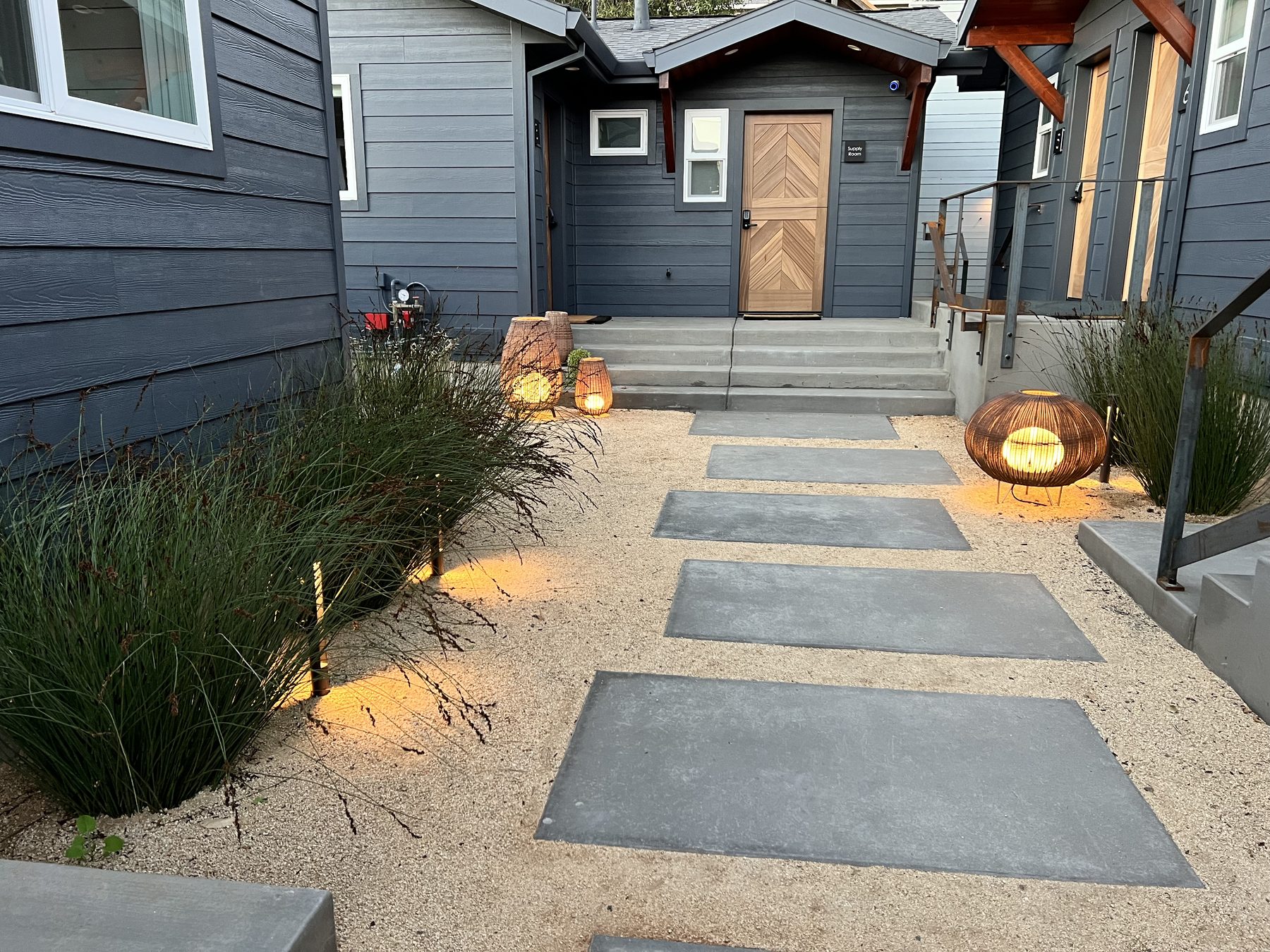 Lantern-lit stone path leading between the blue cottages at Surf Lodge